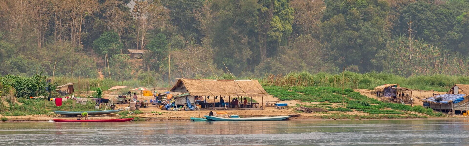 Pak Ou’s tranquil Mekong cliffs in Laos on a Pak Ou Tours banner by Legend Travel Group.